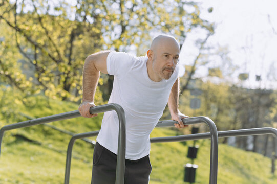 Man Performing Dips Outdoors in a Sunlit Park