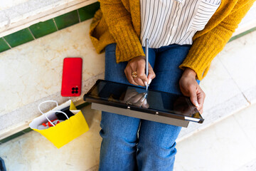 Cuban woman using digital tablet and stylus pen after shopping
