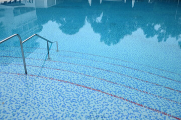 Empty open air swimming pool with clean blue water and line marking on bottom in resort hotel