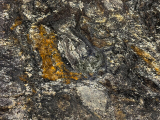 Natural black and white granite slab pattern with orange brown color shades. Shimmering black and grey grains granite with random stone pattern. Natural minerals seamless background texture.