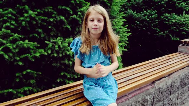 The girl looks at the camera and claps her hands. Applause.