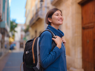 Young woman strolling through charming narrow streets of Denia, Alicante province, Spain, surrounded by historic Mediterranean architecture , enjoying peaceful atmosphere and cultural ambiance.