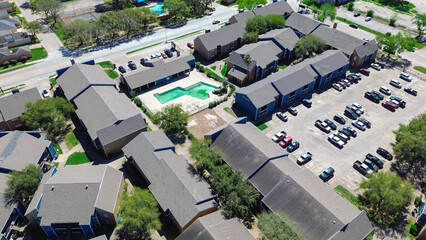 Fototapeta premium Modern multistory apartment complex with swimming pool, uncovered parking lot, shingle roofing along Corporate Drive in fast-growing housing market area, Chinatown, Houston, Texas, aerial view