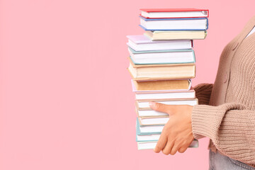 Female hands holding books on pink background