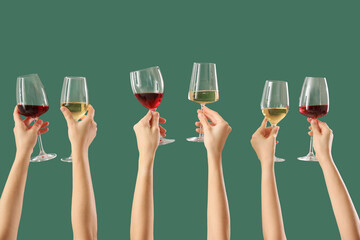 Female hands holding glasses of different wine on green background