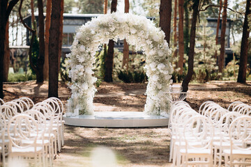 A beautiful wedding scene in a pine forest with white delicate chairs and a soft gypsophila arch....