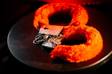 Bright red fur handcuffs on a dark surface create an intriguing contrast in a playful setting
