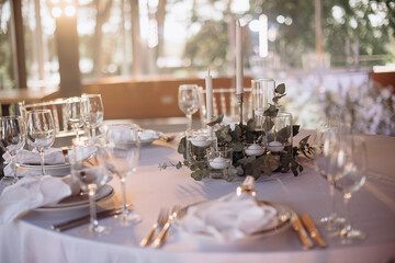 An elegant table setting for a wedding ceremony features white calla lilies, orchids, and freesia in a glass vase. Two candles in glass holders create a cozy, romantic atmosphere