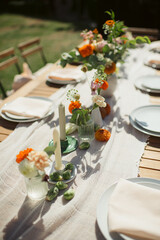 Outdoor table setting with floral arrangements and candles. Warm, summer atmosphere