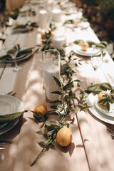 Outdoor festive table with lemons and greenery. Warm, summer atmosphere