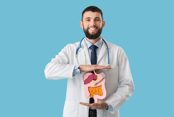 Happy male neurologist with model of digestive system on blue background