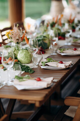Set table with vegetable arrangements and flowers on a wooden surface