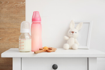 Bottles of baby milk formula and toys on light table at home