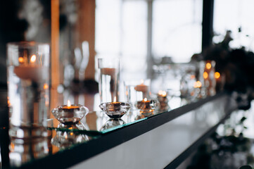 Floating candles in glass globes burning on a mirrored presidium of the newlyweds in a restaurant, creating an elegant and romantic atmosphere for the celebration