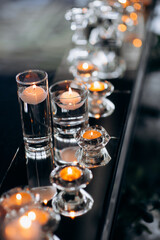 Floating candles in glass globes burning on a mirrored presidium of the newlyweds in a restaurant, creating an elegant and romantic atmosphere for the celebration