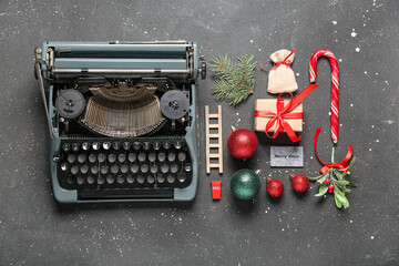 Vintage typewriter with Christmas decorations, gift box, mistletoe and fir branches on black...