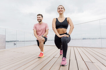Outdoor Fitness Session With Friends Enjoying Lunges on a Cloudy Day by the Water