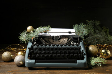 Vintage typewriter with Christmas balls and fir branches on wooden table