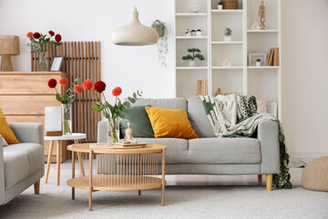 Interior of stylish living room with grey sofas and beautiful dahlia flowers on coffee table