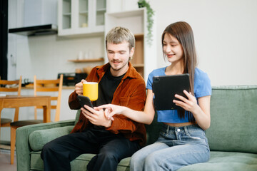 Two man and women enjoy remote work in a cozy living room, using a laptop while sipping coffee and...