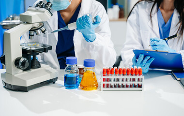 scientists in lab coats conducting research, handling glassware, and working with chemicals