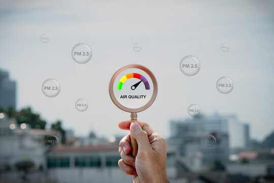 Hand holding a magnifying glass to check the air quality for PM 2.5 over smog city from PM2.5 dust on visibility city background with dangerous haze and fog. health care, pm 2.5 warning.