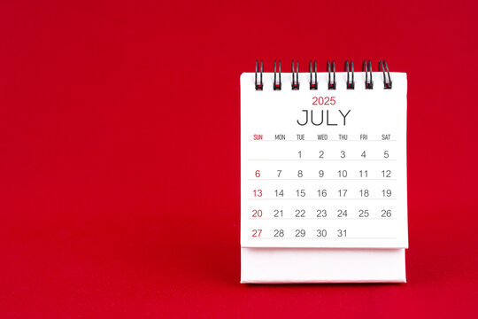 White desk calendar for July 2025 on red background.