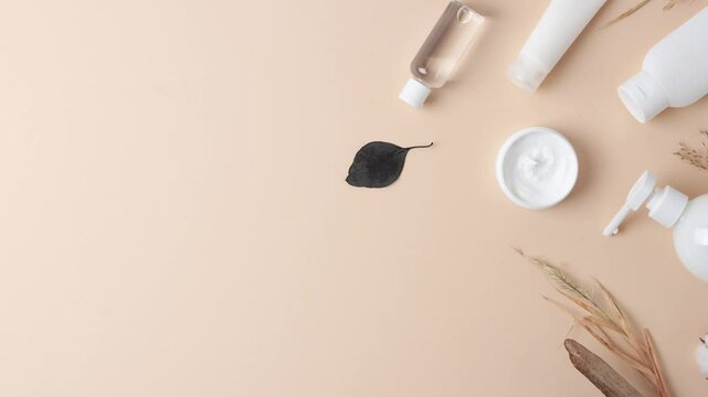 Cosmetic skin care products with flowers and wood on pastel beige background. Flat lay, copy space