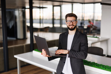 Fototapeta premium Portrait of businessman smiling while using laptop in office