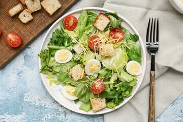 Plate with tasty Caesar salad on blue background