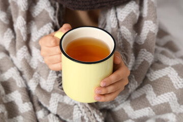 Ill little boy with sore throat and cup of tea in bedroom, closeup