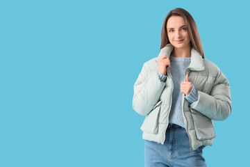 Beautiful young woman in stylish warm clothes on blue background