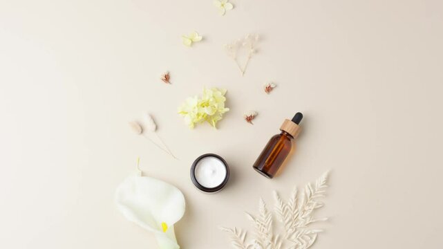 Cosmetic skin care products with flowers on pastel beige background. Flat lay, copy space