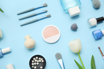 Composition with makeup products, nail polishes, bottle of micellar water and flower on blue background