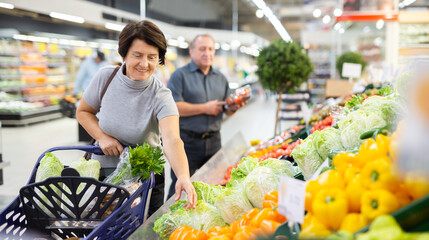 Positive female buyer consumer bell peppers with interest in grocery department of supermarket