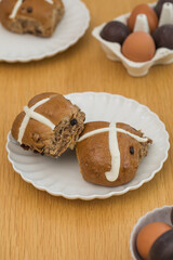 Hot cross buns on white plate on wooden table. Happy Easter