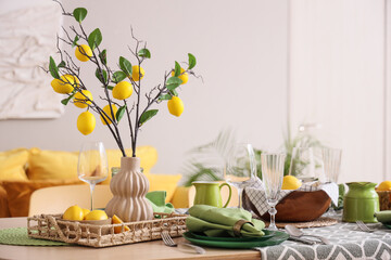Stylish green table setting decorated with many fresh citruses and beautiful lemon tree branches in dining room