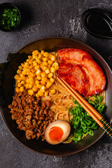A bowl of ramen with noodles, meat and green onions.