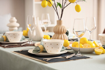 Stylish table setting decorated with many fresh citruses and lemon tree branches in dining room