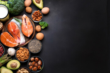 Food sources of omega 3 on dark background with copy space top view. Foods high in fatty acids including vegetables, seafood, nut and seeds.