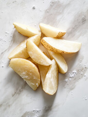 Peeled potato wedges covered the whole white tabletop, 