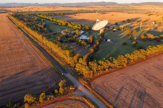 Aerial view of a large satellite dish on rural farmland in late afternoon sunshine
