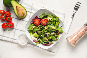 Bowl of tasty avocado salad with cherry tomatoes and sesame seeds on white background