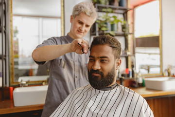 In a modern salon, a skilled barber expertly trims a clients hair, providing an exceptional...