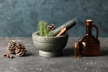 Coniferous cone essential oil with mortar on dark background