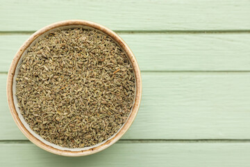 Bowl with aromatic anise seeds on color wooden background