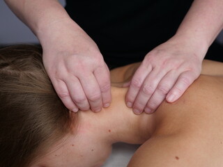 The masseur massages the neck ear for a woman's client to get rid of pain and discomfort in the...