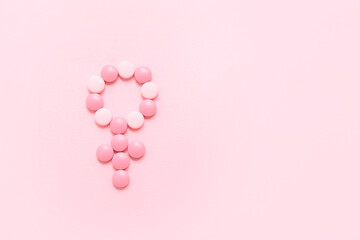 Symbol of woman made of hormonal pills on pink background