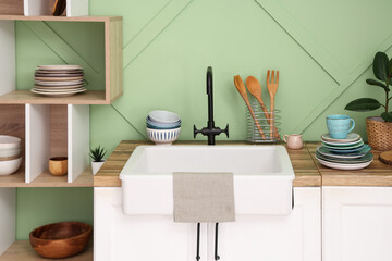 Clean plates, bowls and cup near sink in stylish kitchen, closeup