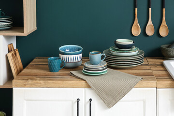 Wooden table with different plates near blue wall in kitchen